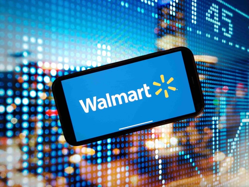 Smartphone displaying the Walmart logo in front of a digital financial market background