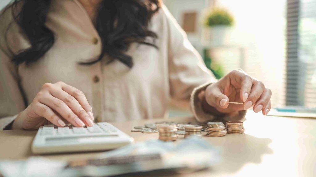 Person using a calculator while sorting coins on a table