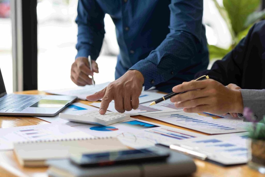 Business professionals reviewing charts, reports, and financial calculations at a desk