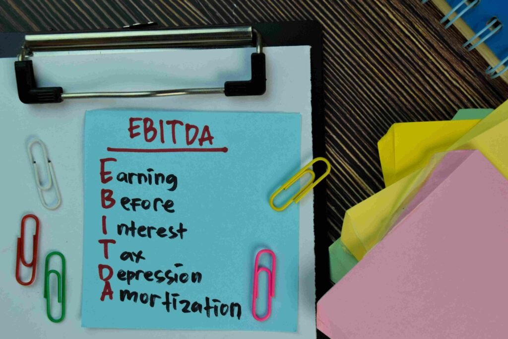 Clipboard with a note listing the components of EBITDA alongside colorful paper clips