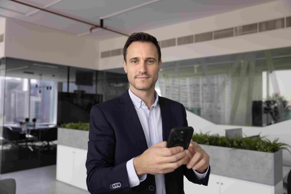 Business professional holding a smartphone in a modern office, representing career growth through professional certifications