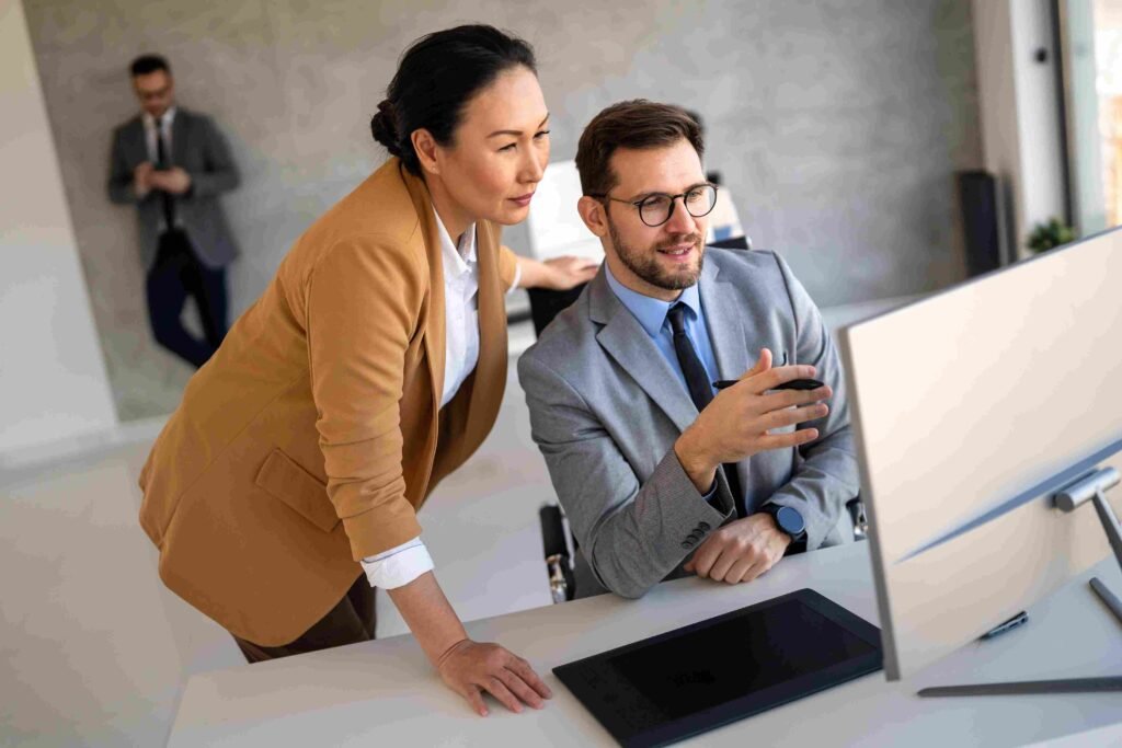 Two financial professionals reviewing information together on a computer in an office setting