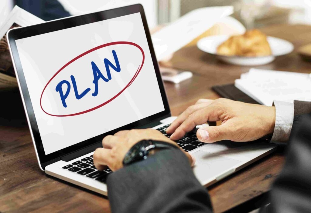 Business professional using a laptop displaying the word “PLAN,” representing workforce planning, performance tracking, and strategic management activities.