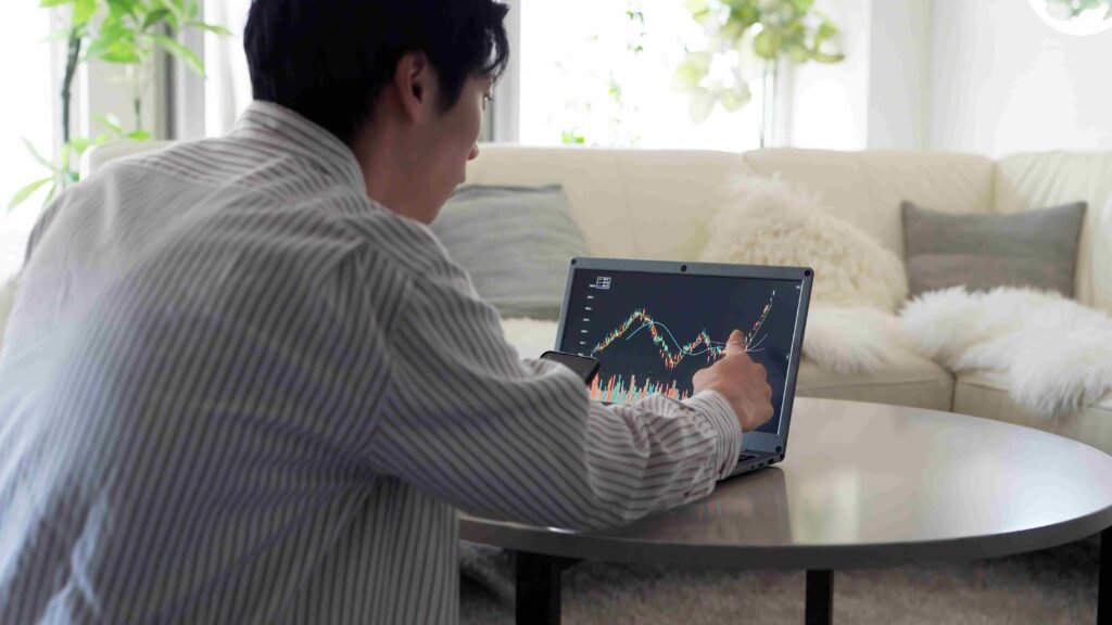 A person reviewing stock market charts on a laptop while analyzing financial data at home.