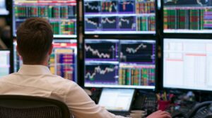 Trader monitoring multiple financial market screens displaying live charts, prices, and trading data